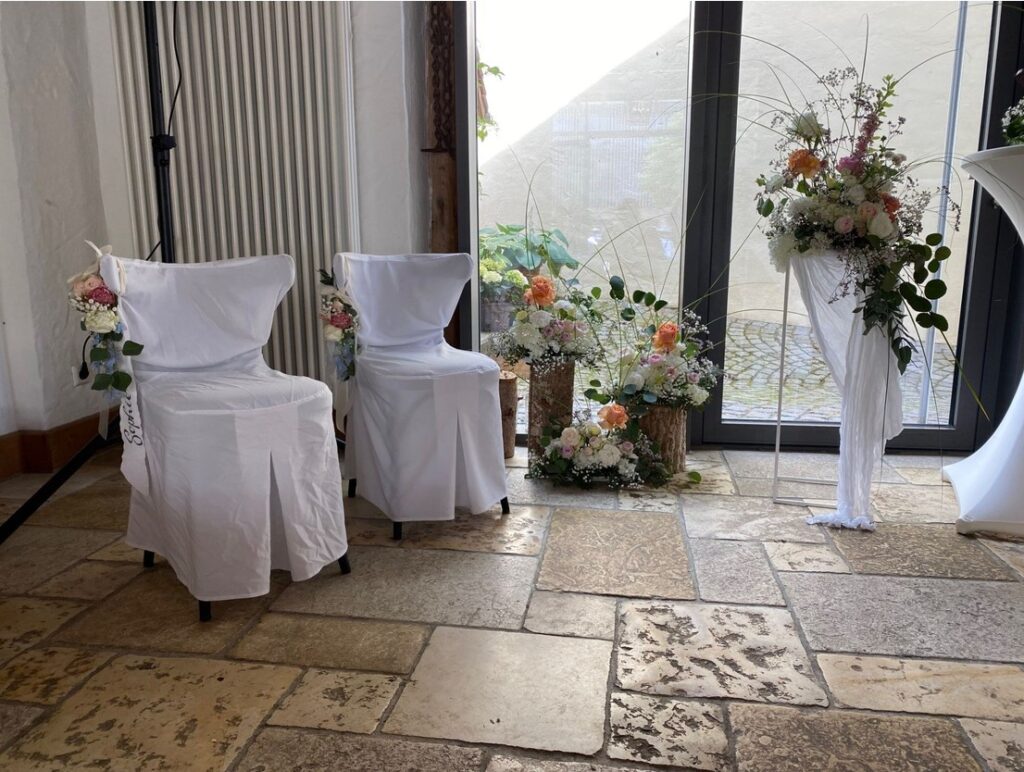 Stühle mit Blumenschmuck warte nauf das Hochzeitspaar Sophie & Stefan am Hofgut Maisenburg Landkreis Reutlingen